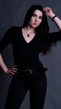 Pretty young sexy model female with dark hair in amazing long red dress and black shoes posing in dark studioの写真素材