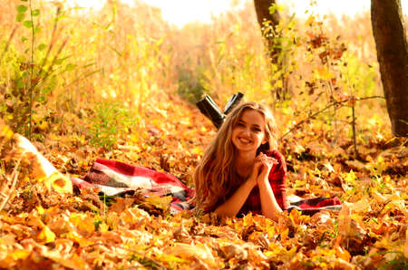 Outdoor fashion photo of young beautiful lady surrounded autumn leavesの写真素材