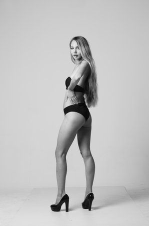 Sexy blonde woman in black lingerie posing on gray background.の写真素材