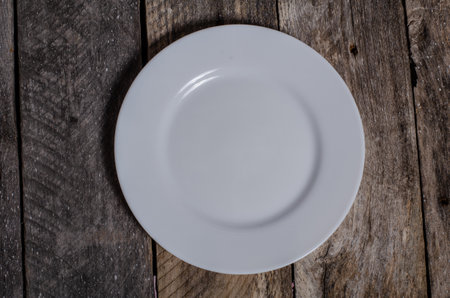Empty white plate on wooden background. Top view, copy space.の写真素材