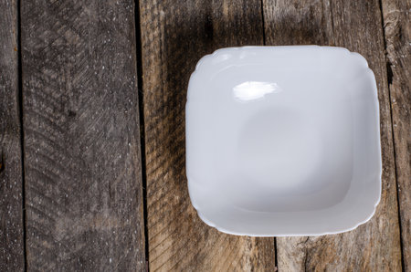 Empty white porcelain bowl on old wooden table, top viewの写真素材