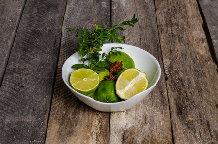 Lime and mint leaves in a bowl on a wooden background.の写真素材