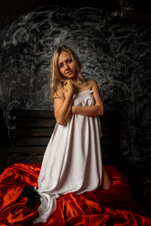 Topless blonde, covered with a white cloth on a black backgroundの写真素材
