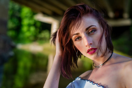 Portrait of a beautiful young woman on the background of a bridgeの写真素材