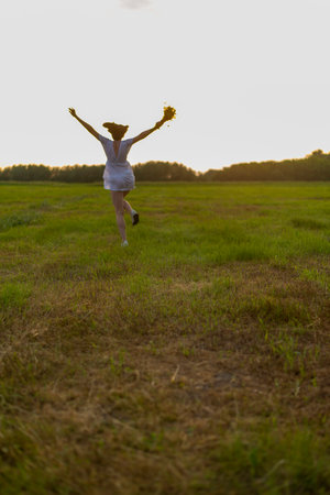 Portrait of a beautiful red-haired girl in the poppies meadow at sunset.の写真素材