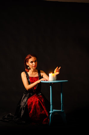 Mysterious magic close-up - women's hands conjure over a burning candle in isolation on a black background. The concept of prediction, clairvoyance and divination.の写真素材