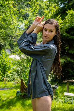 Portrait of beautiful smiling woman catching water drops at gardenの写真素材