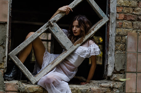 Beautiful girl in a white dress on the ruins of an old houseの写真素材