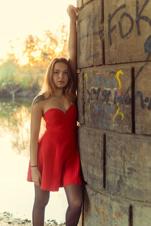 Beautiful girl in a red dress on the background of the riverの写真素材
