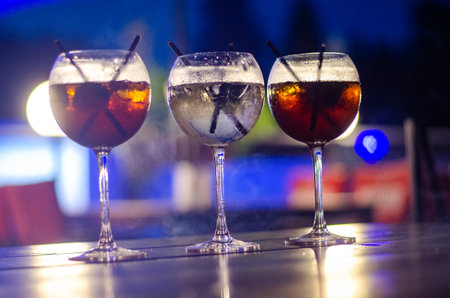 Three glasses of cocktails with ice on the table in the night clubの写真素材
