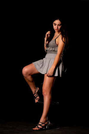 Beautiful young woman in a gray dress on a black background.の写真素材
