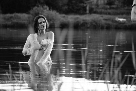 Young beautiful girl in a white dress on a background of water.の写真素材