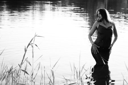 Black and white portrait of a beautiful young woman by the lake.の写真素材