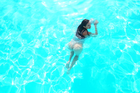 wet Seductive brunette in a sexy dress in the pool.