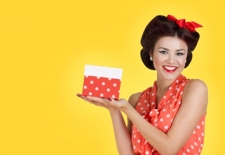 Portrait of beautiful brunette girl holding a gift box. Retro pin-up styleの写真素材