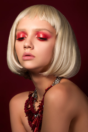 Fashion portrait of young blonde girl over wine red backgroundの写真素材