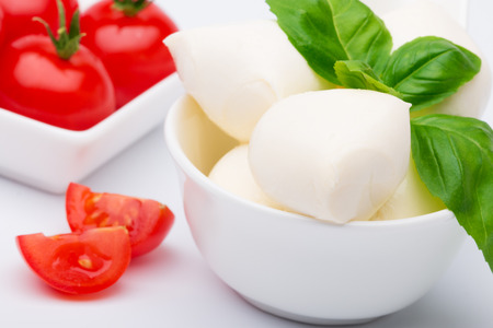 Mozzarella, fresh tomatoes and basil leaves lying in bowlの写真素材