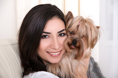 Portrait of young beautiful woman playing with her dogの写真素材