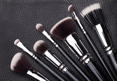 Set of professional makeup brushes over black leather background