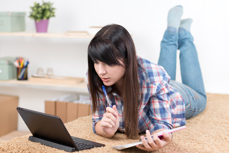 Teenager girl studying at home lying on sofaの写真素材
