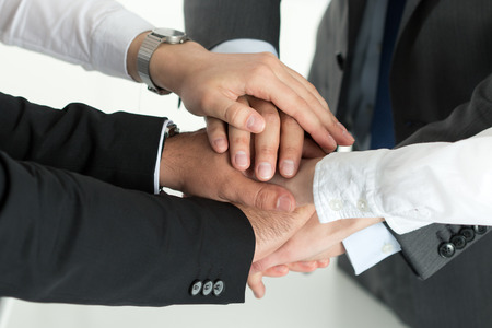 Closeup of business team showing unity with putting their hands together on top of each other. Concept of teamwork.の写真素材