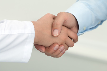 Female medicine doctor shaking hands with male patient. Partnership, trust and medical ethics concept. Handshake with satisfied client. Healthcare and medical conceptの写真素材