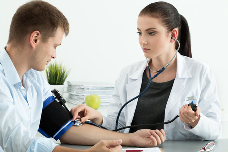 Young female medicine doctor measuring blood pressure to patient. Medical and healthcare conceptの写真素材