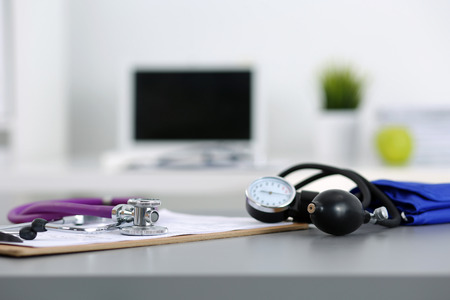 Medicine doctor's working place. Stethoscope and manometer lying on table at physician's office. Healthcare and medical concept