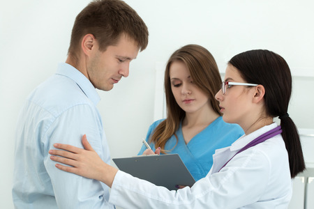 Friendly female doctor touching male patient's arm for encouragement and empathy with her collegue...