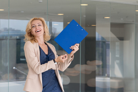 Happy excited business woman celebrating and dancing in her officeの写真素材