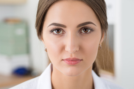 Close-up portrait of young serious medicine doctor sitting at her office. Healthcare and medical conceptの写真素材