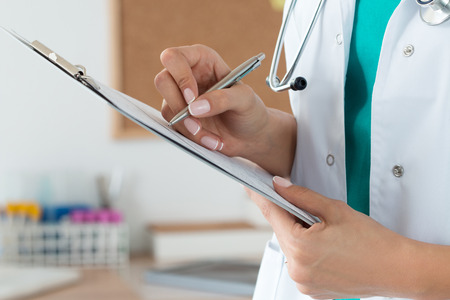 Close-up view of female doctor's hands filling patient registration or prescription form. Healthcare, medical and pharmacy concept.の写真素材