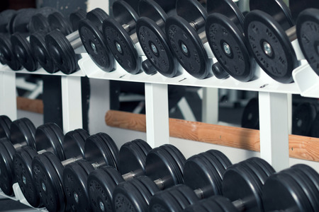 Close-up view of barbells organized in row on rack at gymの写真素材