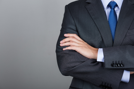 Business man with folded hands against gray background. Copy space