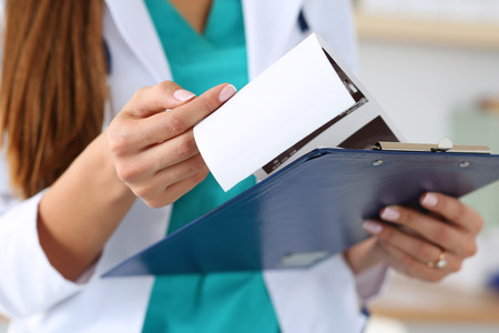 Close-up view of female doctors hands holding patient's medical record. Healthcare and medical conceptの写真素材