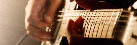 Hands of man playing electric guitar. Bend technique. Low key photo. Letter box format