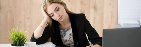 Tired business woman sitting at her working place. Overwork, working overtime and stress at work concept. Letter box formatの写真素材