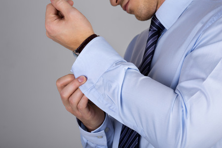 Man fastens his cuff links close-up. Businessman or fiance preparing himself for going out.