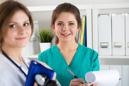 Two beautiful female medicine doctors working at their office discussing patient diagnose. Medical service, education, therapy and healthcare conceptの写真素材