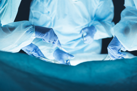 Medical team performing operation. Group of surgeon at work in operating theater toned in blueの写真素材