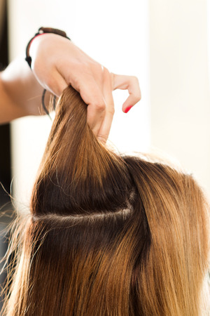 Close up view of hairdresser hand holding strand of hair preparing to cutting and dyeing hair. Haircare, making new hairdo, keratin restoration and hair therapy conceptの写真素材