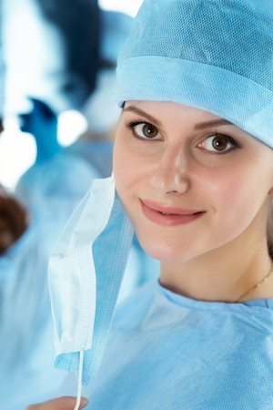 Close up portrait of young female surgeon doctor surrounded by her team. Group of surgeon in operation theatre. Healthcare, medical education, emergency medical service and surgery conceptの写真素材