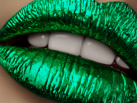 Close up view of beautiful woman lips with green metallic lipstick. Open mouth with white teeth. Cosmetology, drugstore or fashion makeup concept. Beauty studio shot. Passionate kissの写真素材