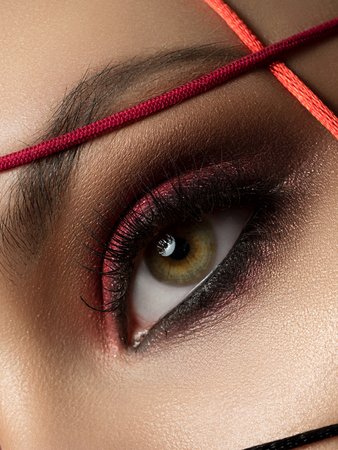 Close up fashion portrait of young beautiful woman with modern trendy makeup. Dark red smokey eyes. Studio shot.の写真素材
