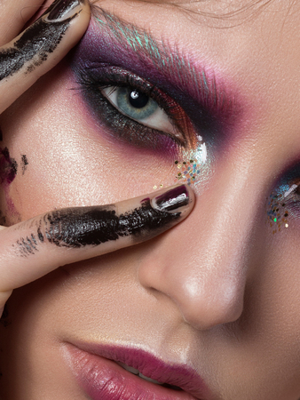 Beauty portrait of a young girl with fashion creative make-up. Colorful smoky eyes. Studio shot. Sensuality, passion, trendy youth makeup concept. Extreme closeup, partial face viewの写真素材