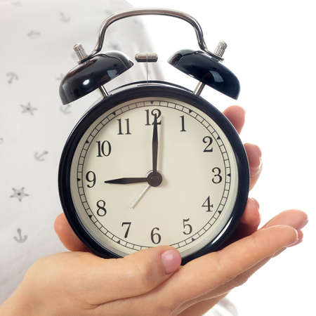 Woman hands holding black alarm clock