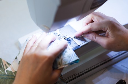 Seamstress hands at work, threads and needles, sewing machineの写真素材