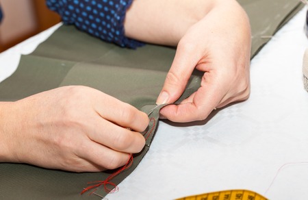 Seamstress hands at work, threads and needles, sewing machine