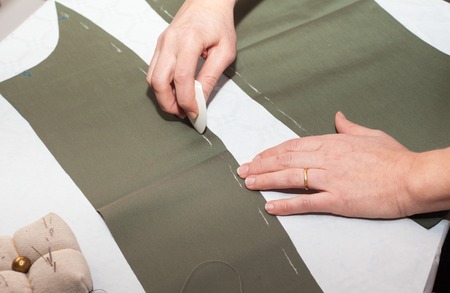 Seamstress hands at work, threads and needles, sewing machine