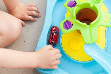 Child's hand playing with water game, car, star, boatの写真素材